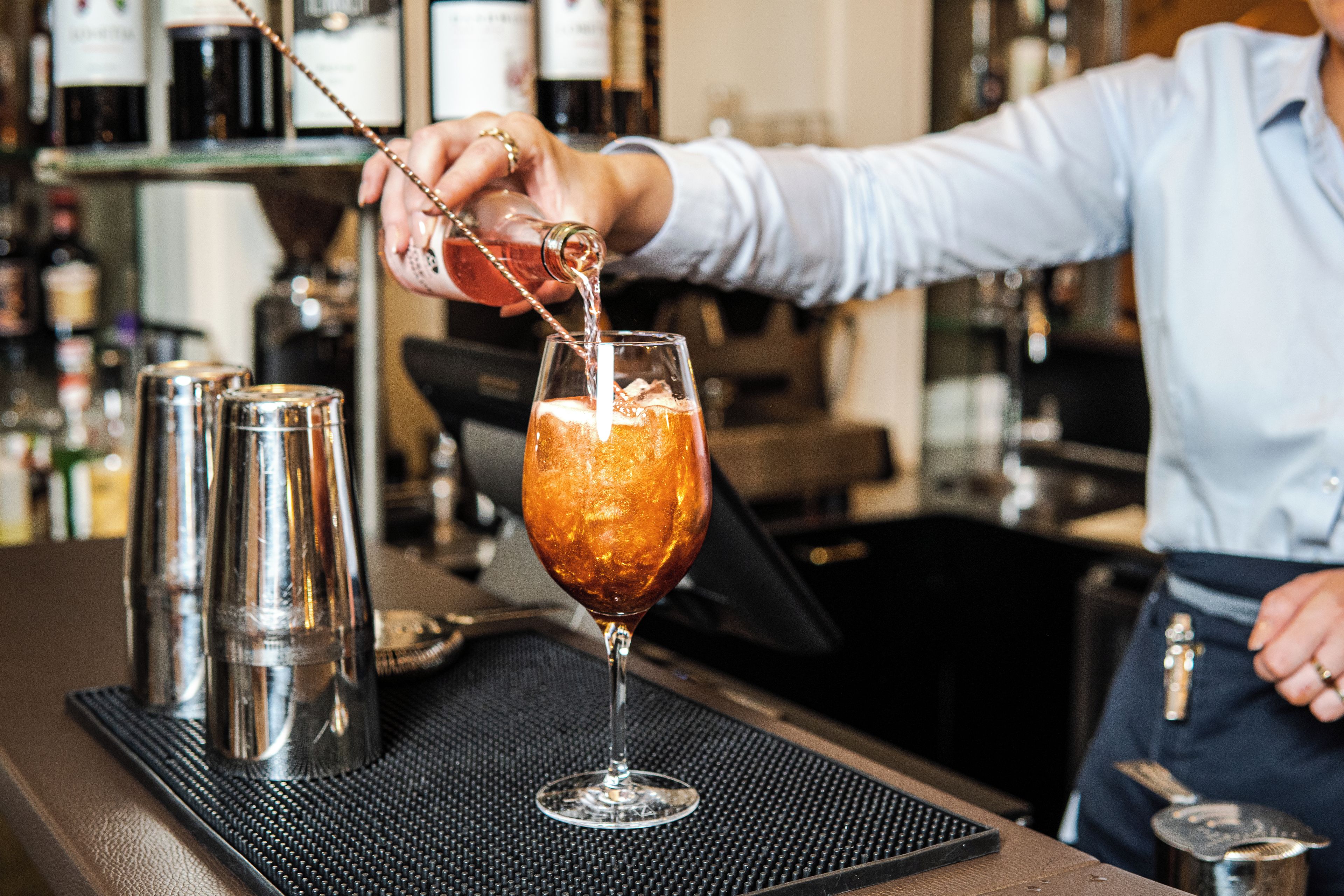 A bartender pouring a drink into a glass.