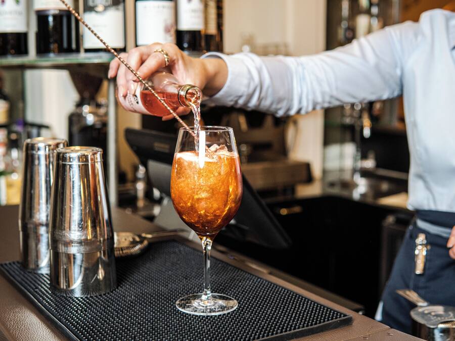 A bartender pouring a drink into a glass.