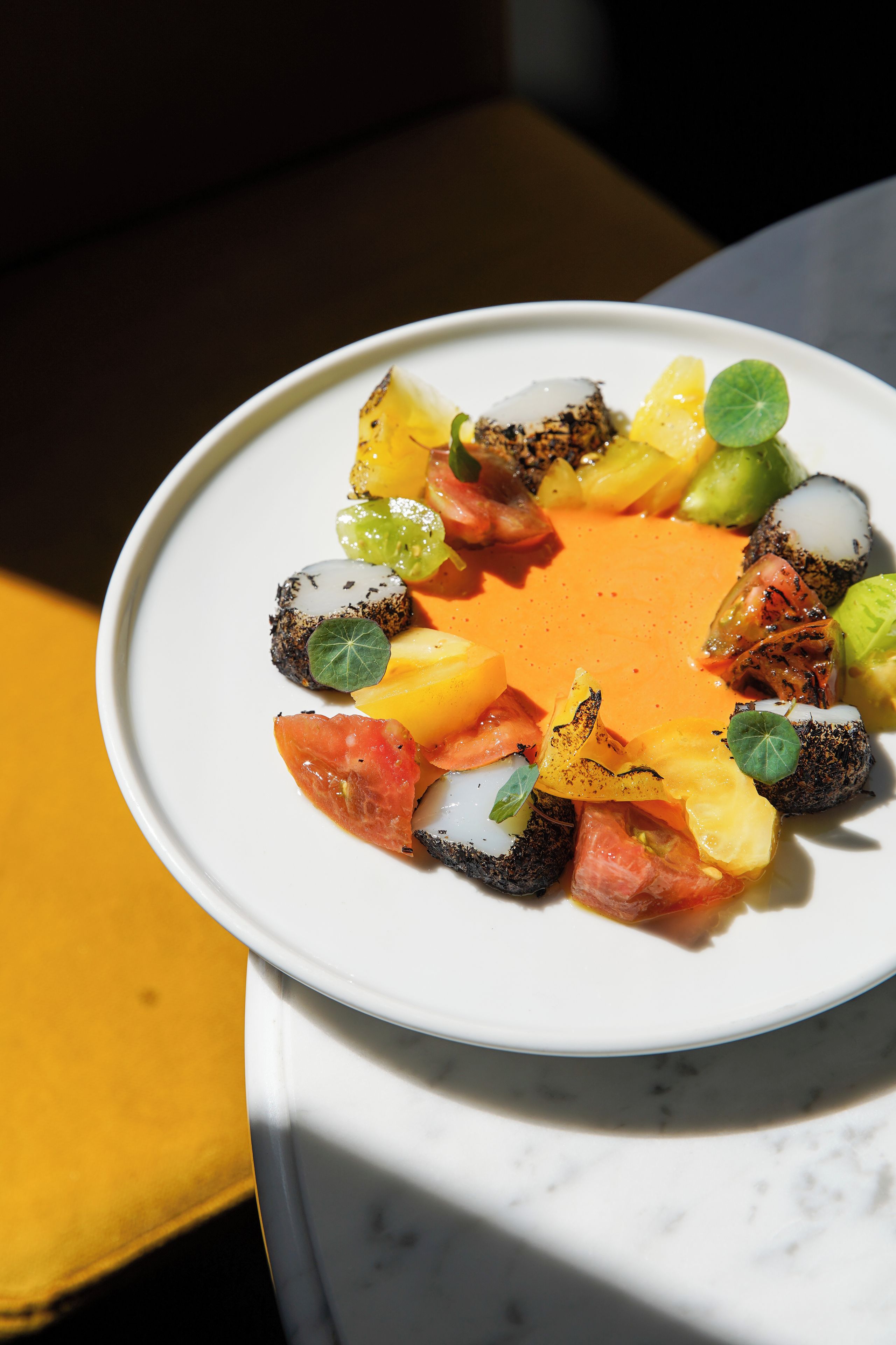 A white plate with a variety of food items including fruits, vegetables, and a sauce.