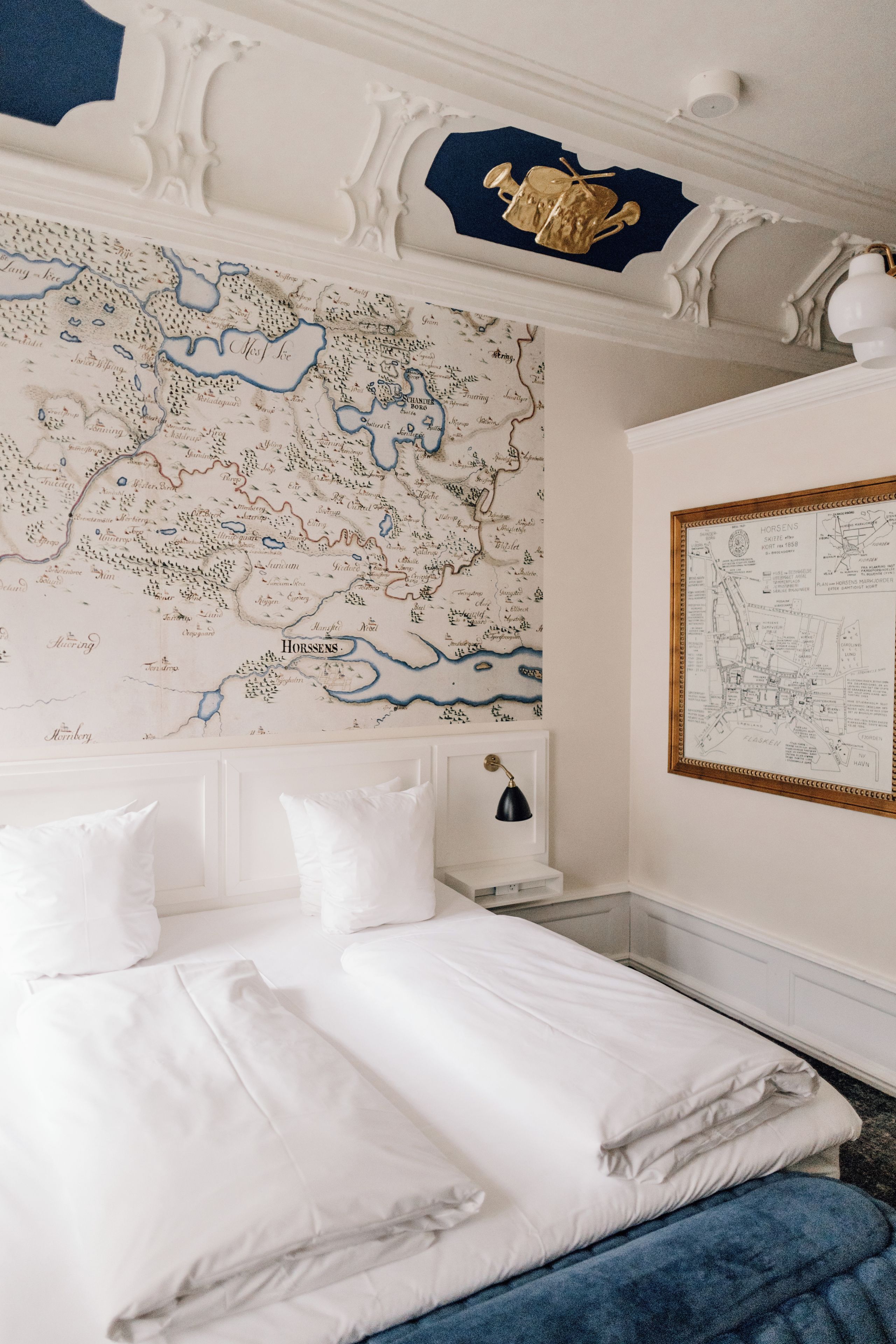 A bedroom with a large bed, a map on the wall, and a framed map on the side.