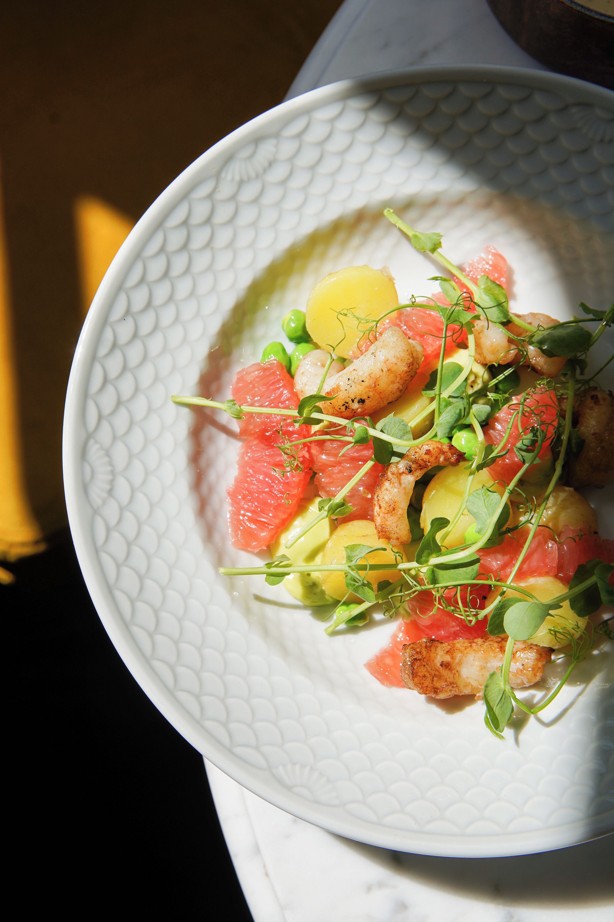 A white plate with a textured pattern, containing a dish with various ingredients.