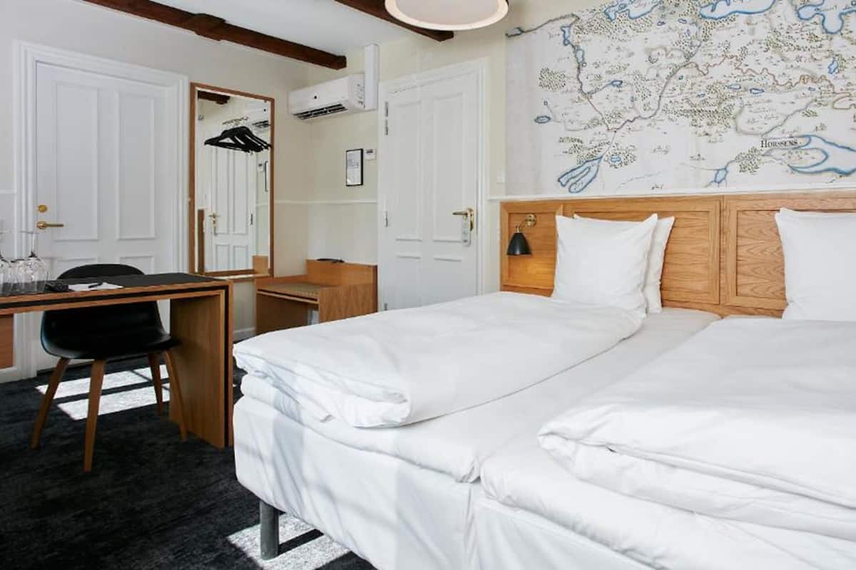 Une chambre d’hôtel avec deux lits, un bureau, une chaise, une carte accrochée au mur et un miroir.