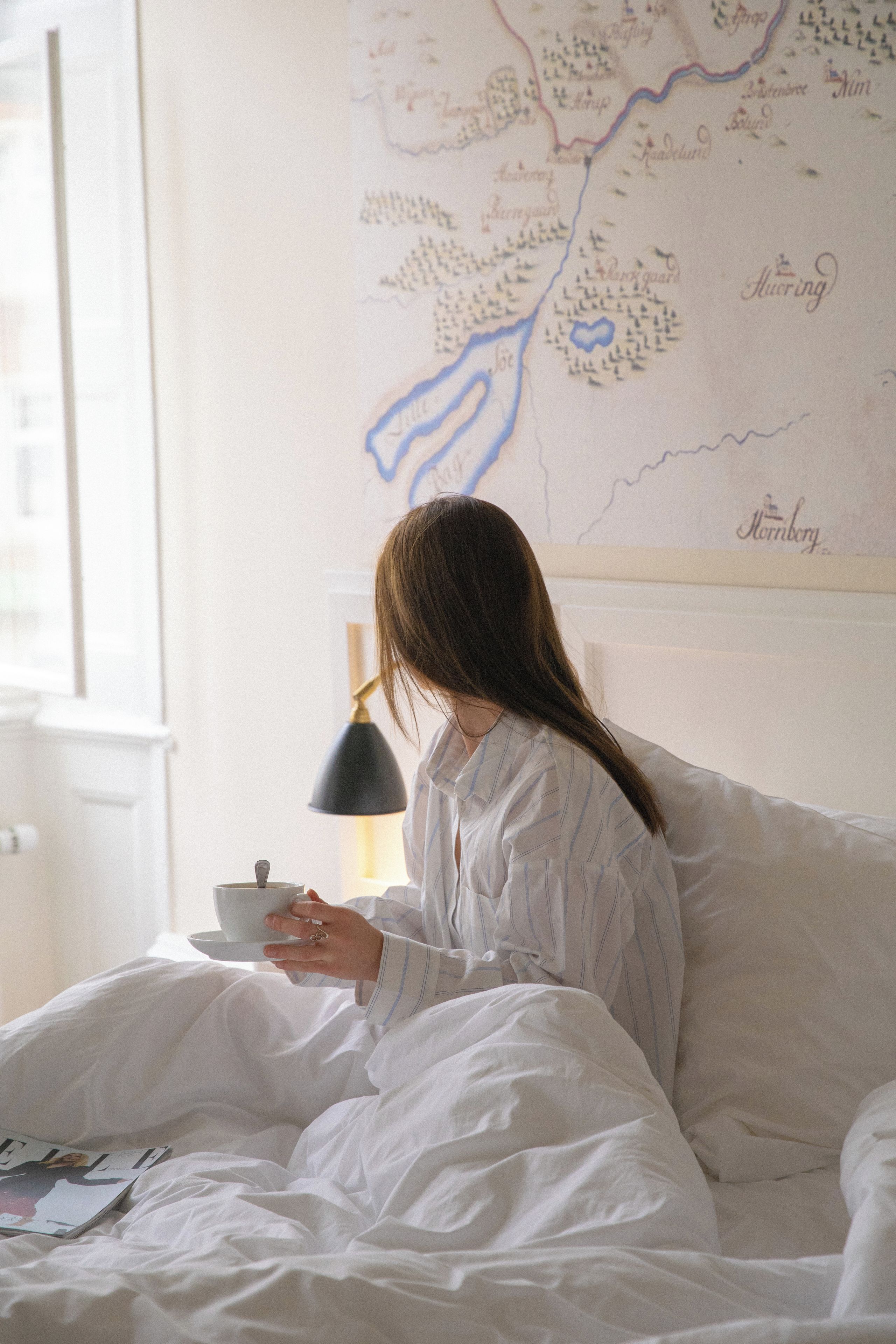 A person sitting on a bed with a map on the wall behind them.