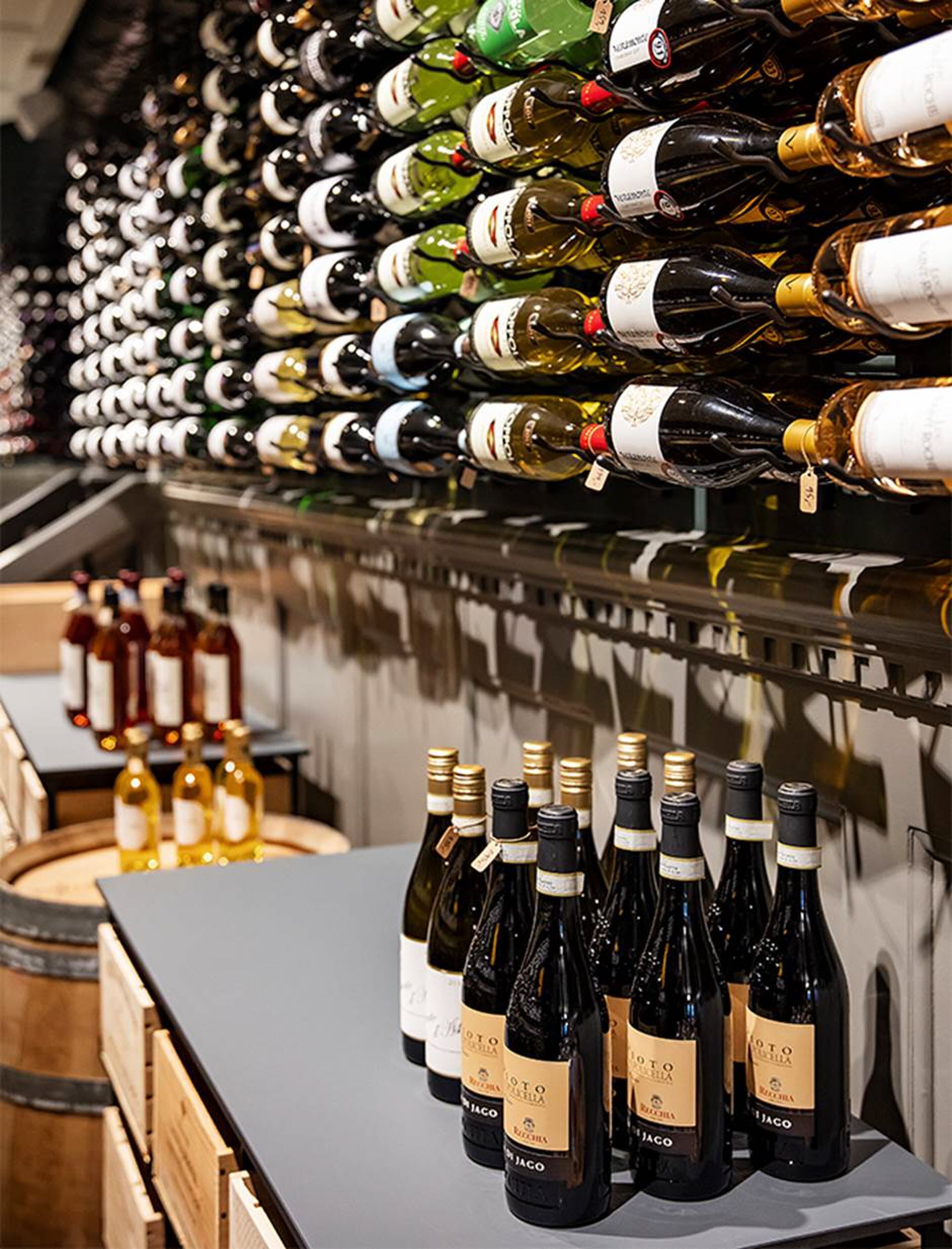 A wine cellar with rows of wine bottles on shelves and a counter with more bottles.