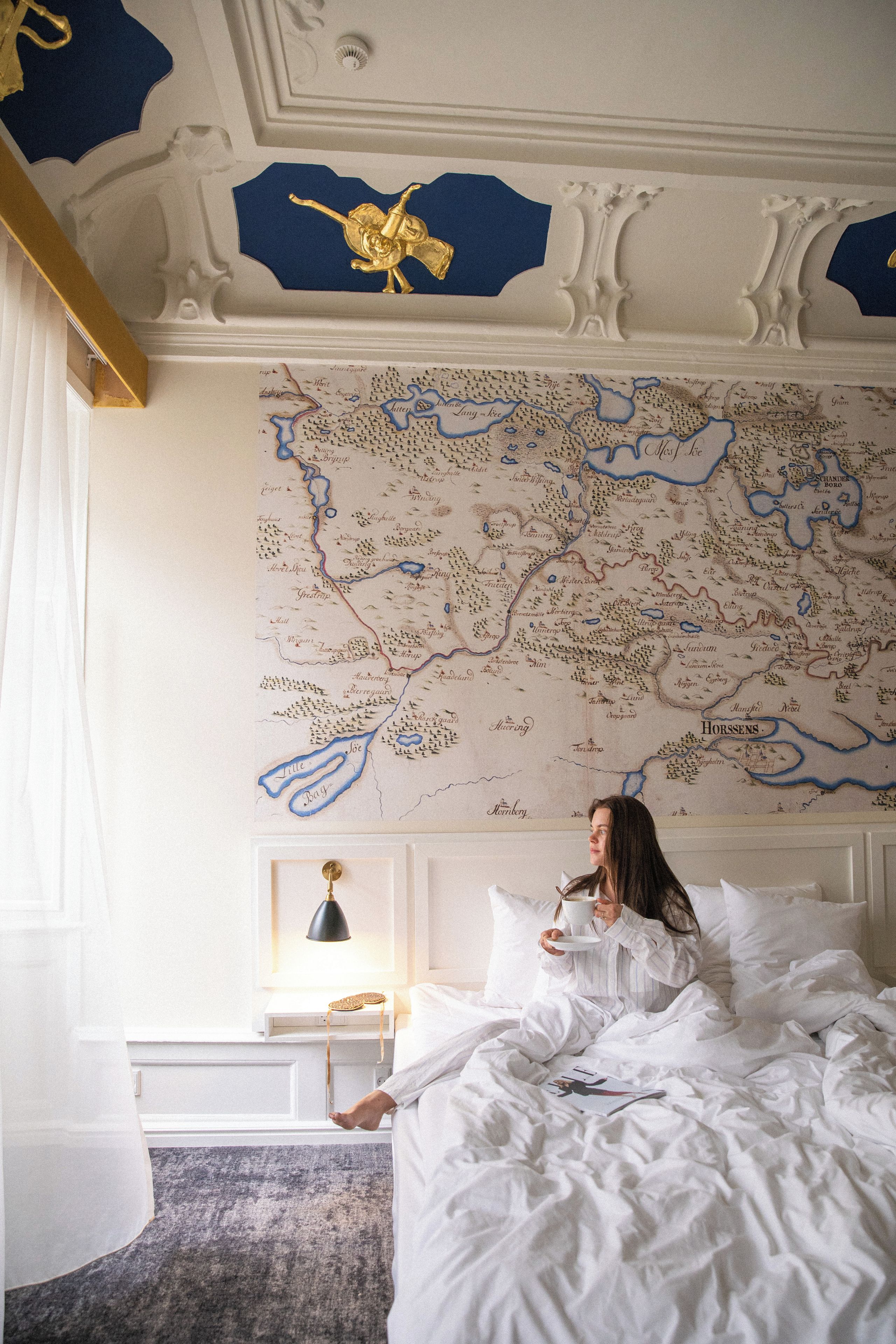 Una persona acostada en una cama en una habitación con un mapa grande en la pared.