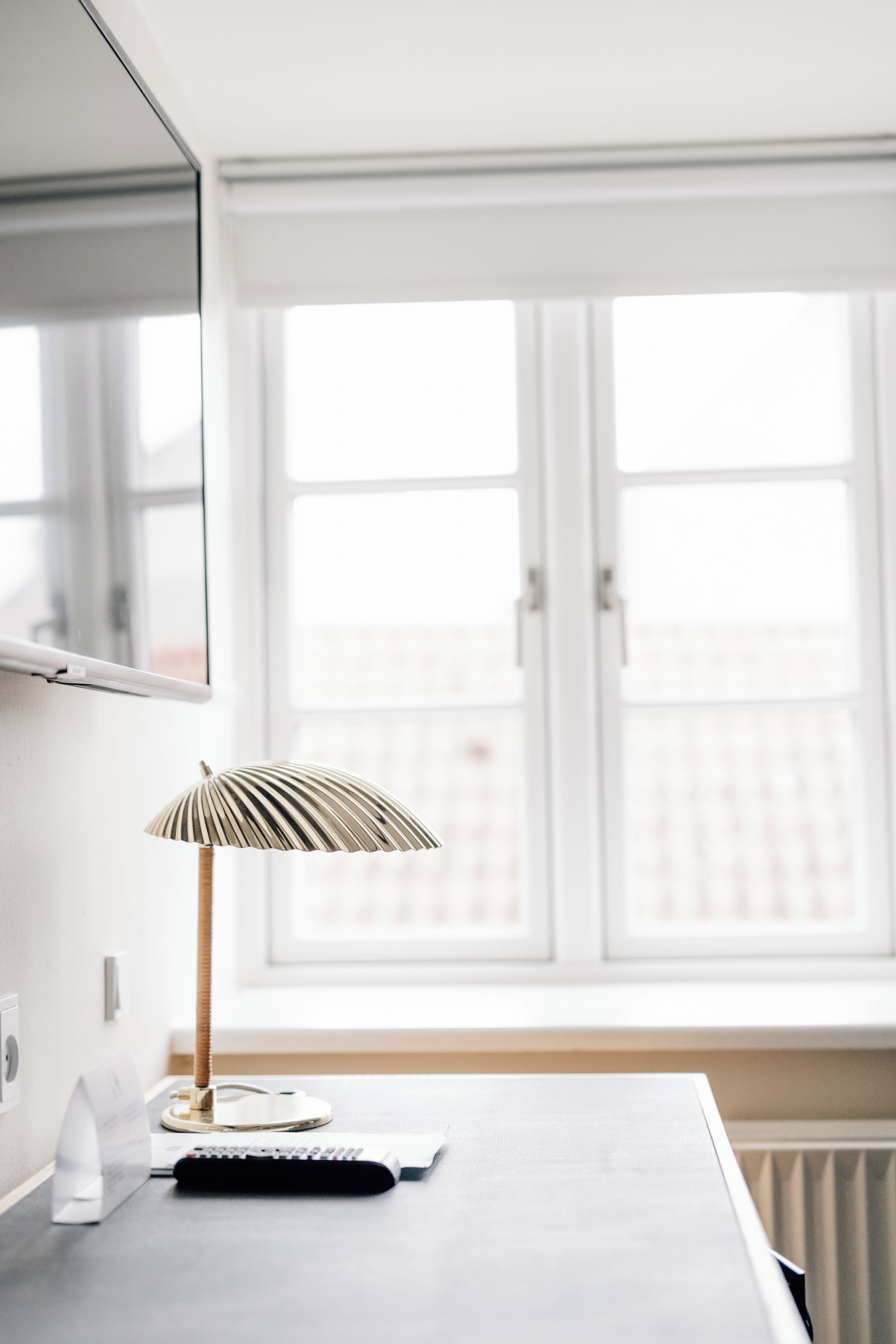 A room with a desk, a lamp, a keyboard, and a window.