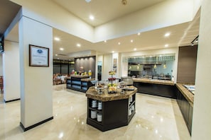 A modern kitchen with granite countertops, stainless steel appliances, and a breakfast bar with fruit and pastries. - Courtyard by Marriott San Luis Potosi (San Luis Potosi)