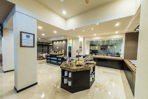 A modern kitchen with granite countertops, stainless steel appliances, and a breakfast bar with fruit and pastries.