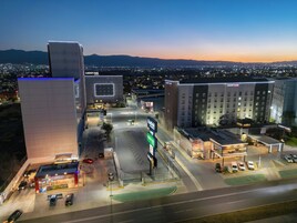 A hotel with a modern design, a parking lot, and a view of the cityscape at dusk.