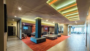 Un hall amplio con asientos modernos, un televisor y una alfombra roja.