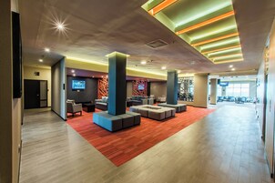 A spacious lobby with modern seating, a TV, and a red carpet.