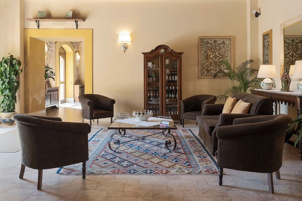 A spacious living room with a large wooden cabinet, two armchairs, a sofa, and a coffee table.