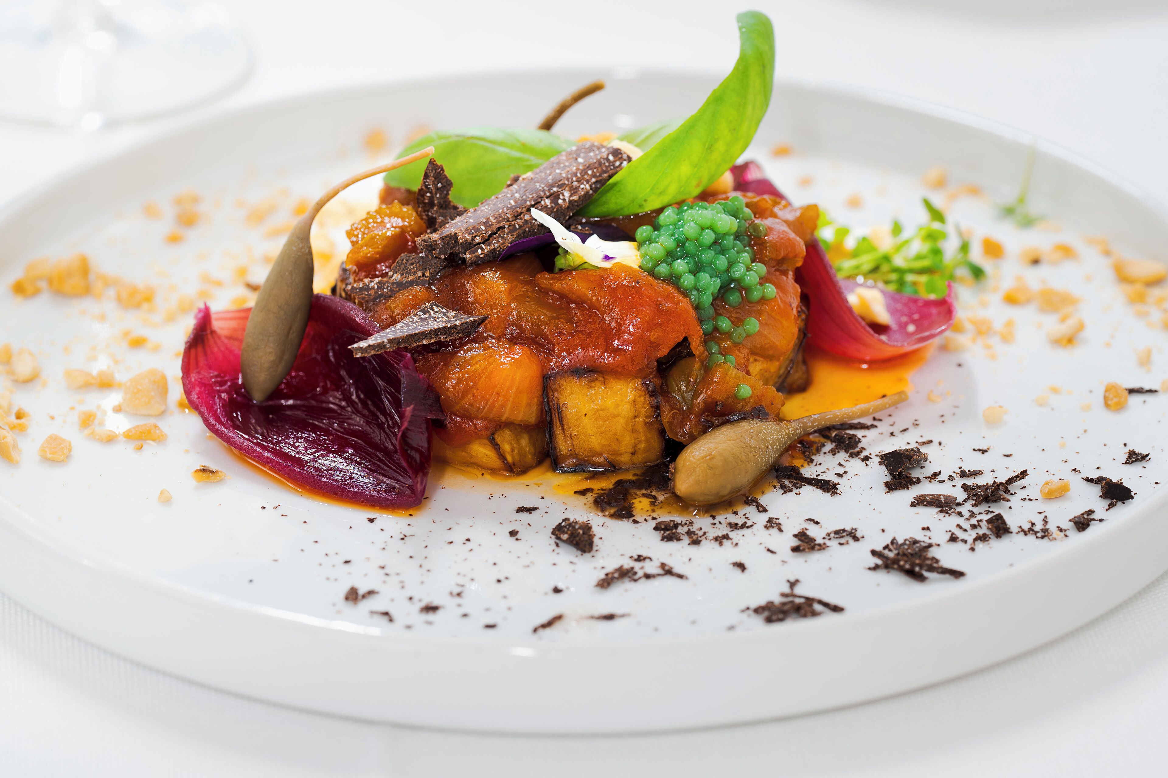 A white plate with a colorful dish of vegetables and garnishes.