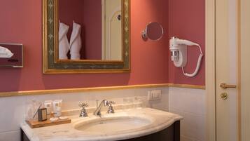 Un bagno con uno specchio grande, un lavandino doppio, un portasciuga e un asciugacapelli fissato alla parete.