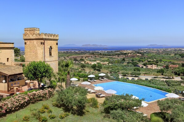A pool area with umbrellas, a bar, and a tower. - Baglio Oneto dei Principi di San Lorenzo - Luxury Wine Resort (Marsala)
