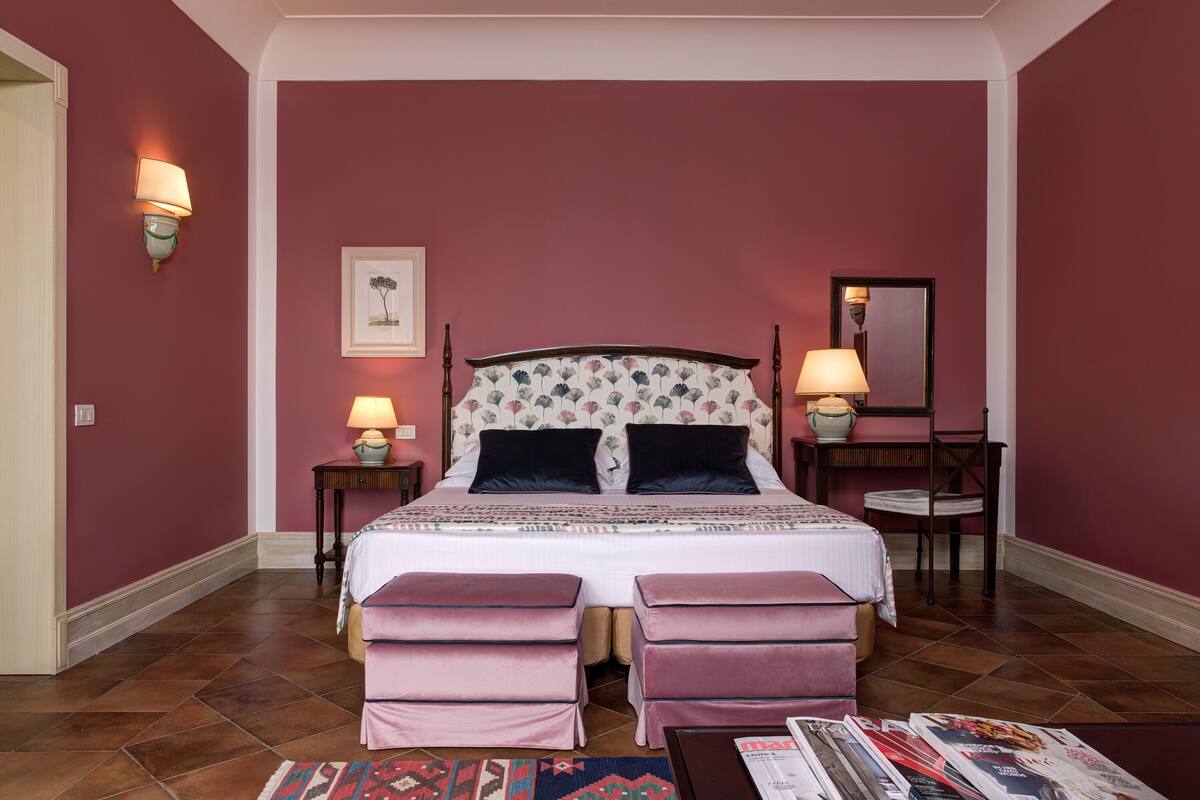 Un dormitorio con una cama grande, dos mesitas de noche con lámparas, un espejo y una alfombra.