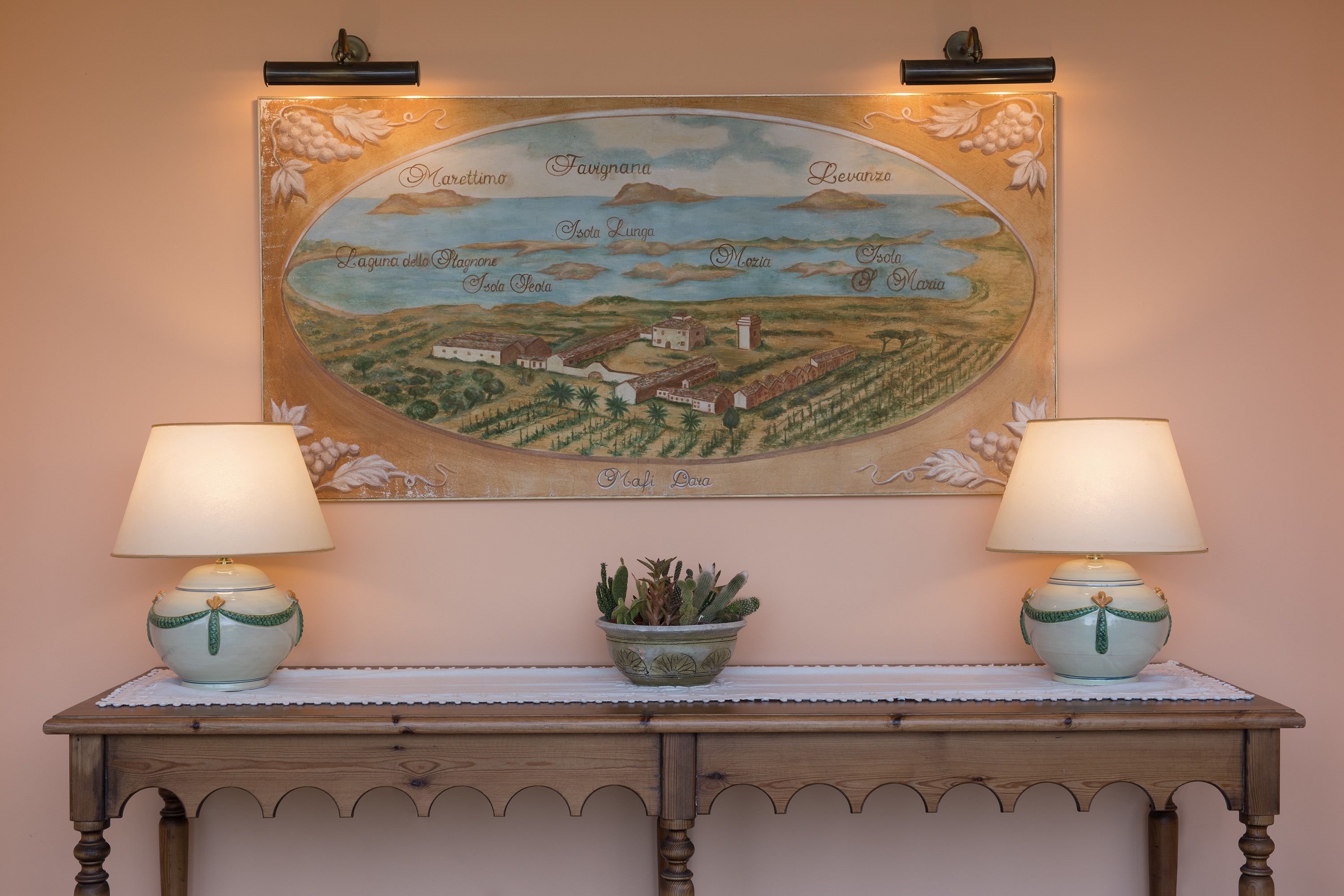 A wall-mounted map with a table featuring two lamps and a potted plant.