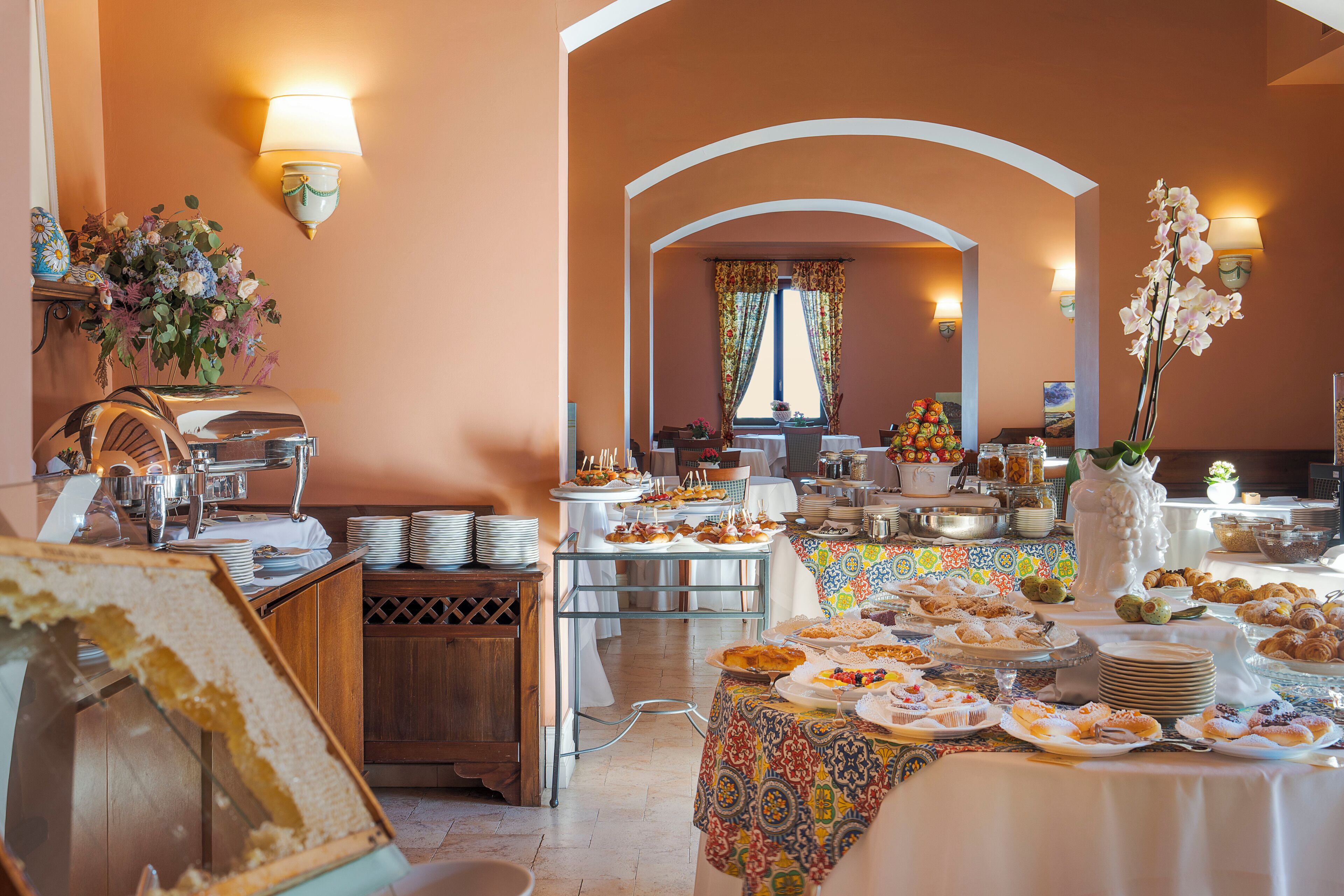 A buffet setup with various food items and a floral centerpiece.