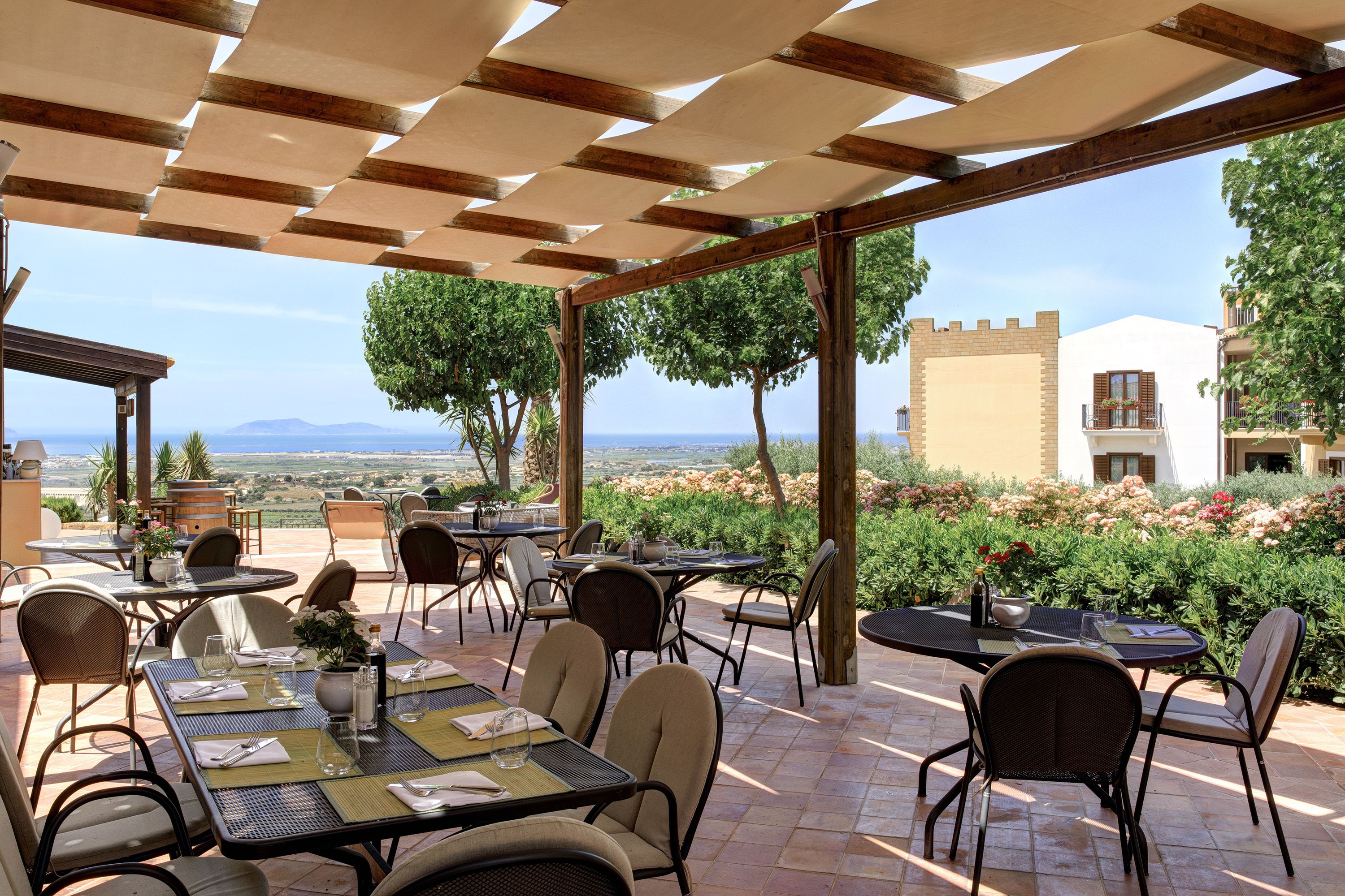 An outdoor patio with tables and chairs, overlooking a scenic landscape.