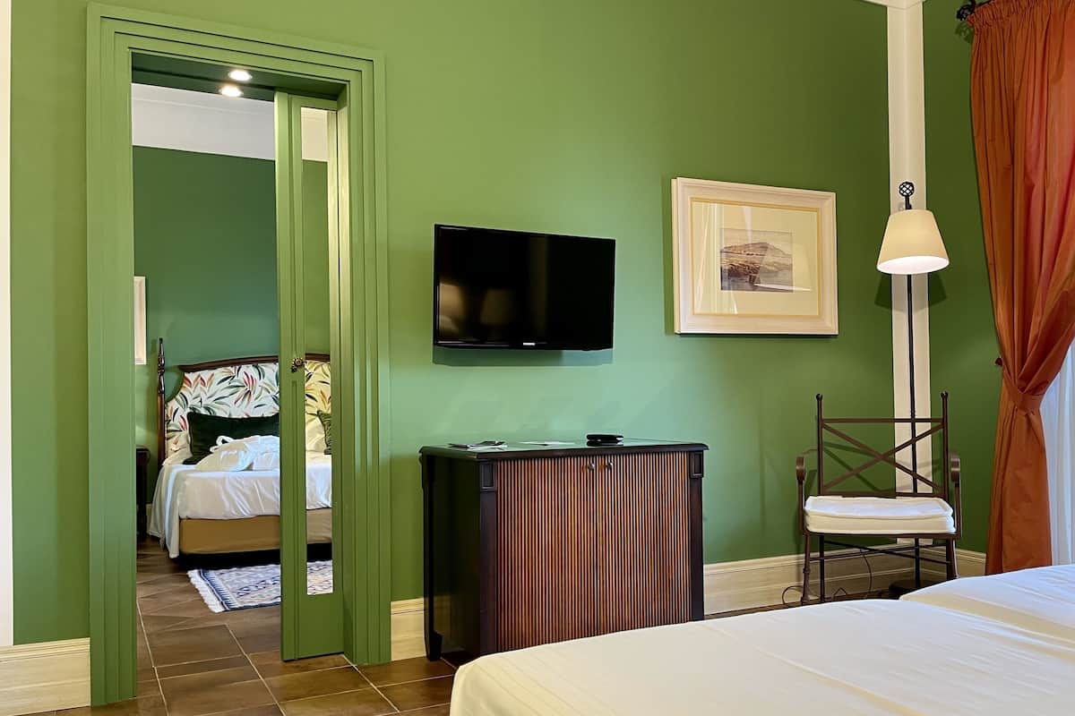 Habitación de hotel con cama, televisión, un cuadro enmarcado y un escritorio con silla.