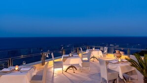 Una terraza con mesas y sillas, con vista al océano.