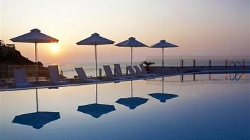 Una piscina al aire libre de temporada, sombrillas, tumbonas