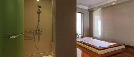 Un baño moderno con ducha a ras de suelo, una bañera independiente y una puerta verde.