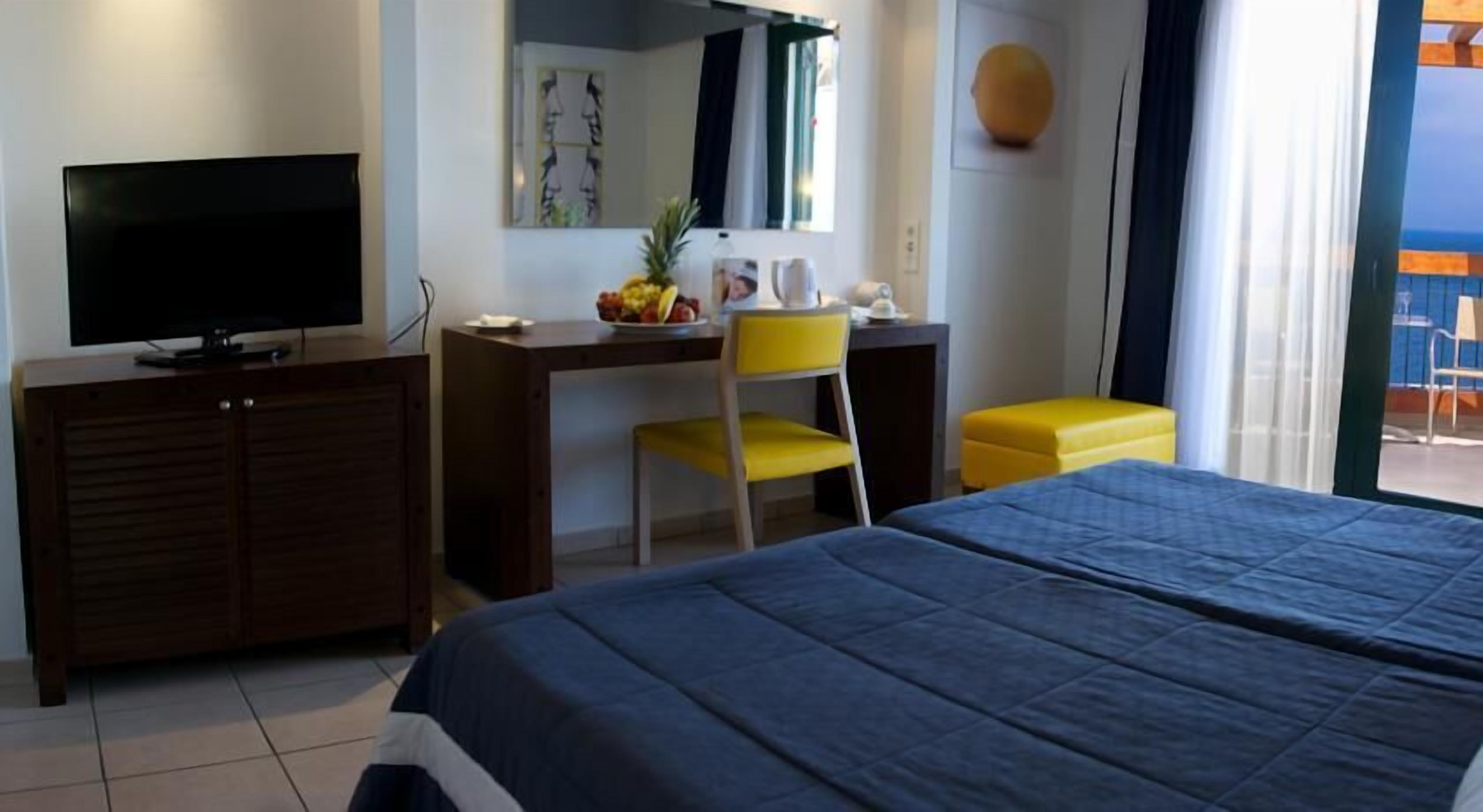 Ein Hotelzimmer mit Bett, Schreibtisch, Sessel, Fernseher und Fenster mit Blick.