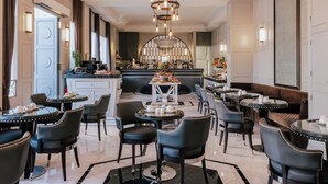A hotel lobby with a bar area, seating arrangements, and a chandelier.