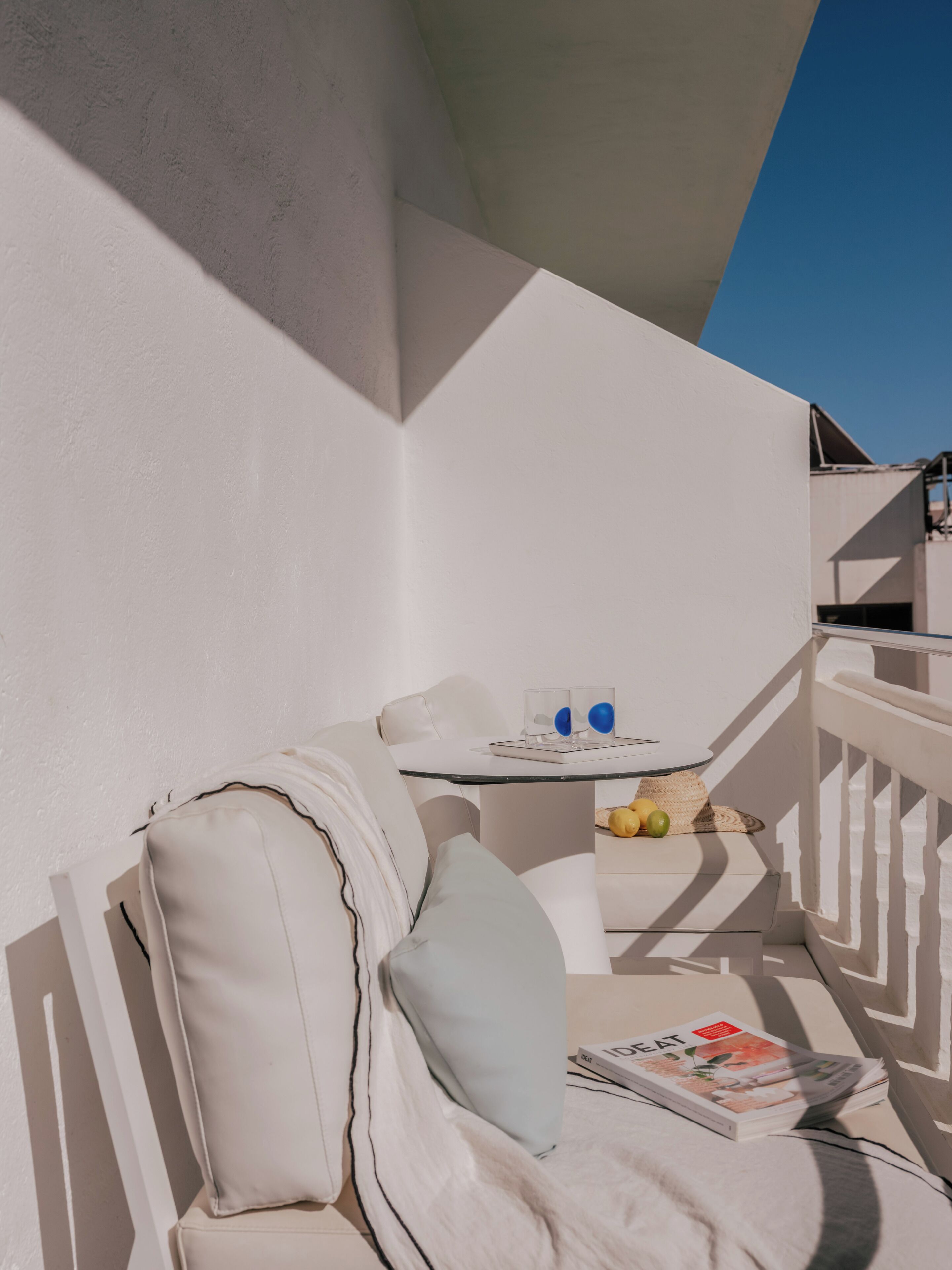 A balcony with a white sofa, a small table with fruits, and a magazine.