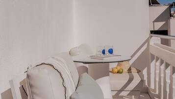 A balcony with a white sofa, a small table with fruits, and a magazine.