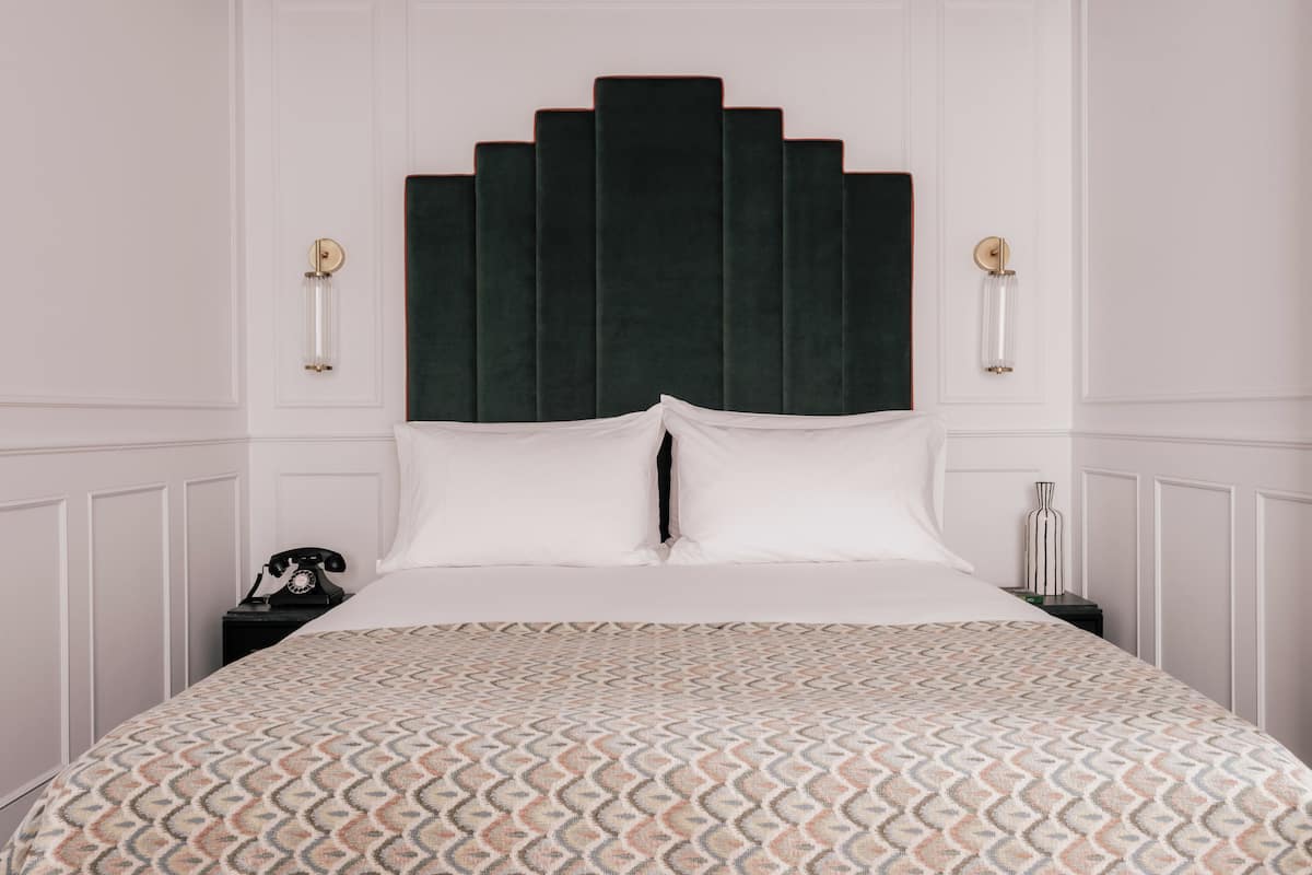 A bed with a patterned bedspread, a dark headboard, and bedside lamps.