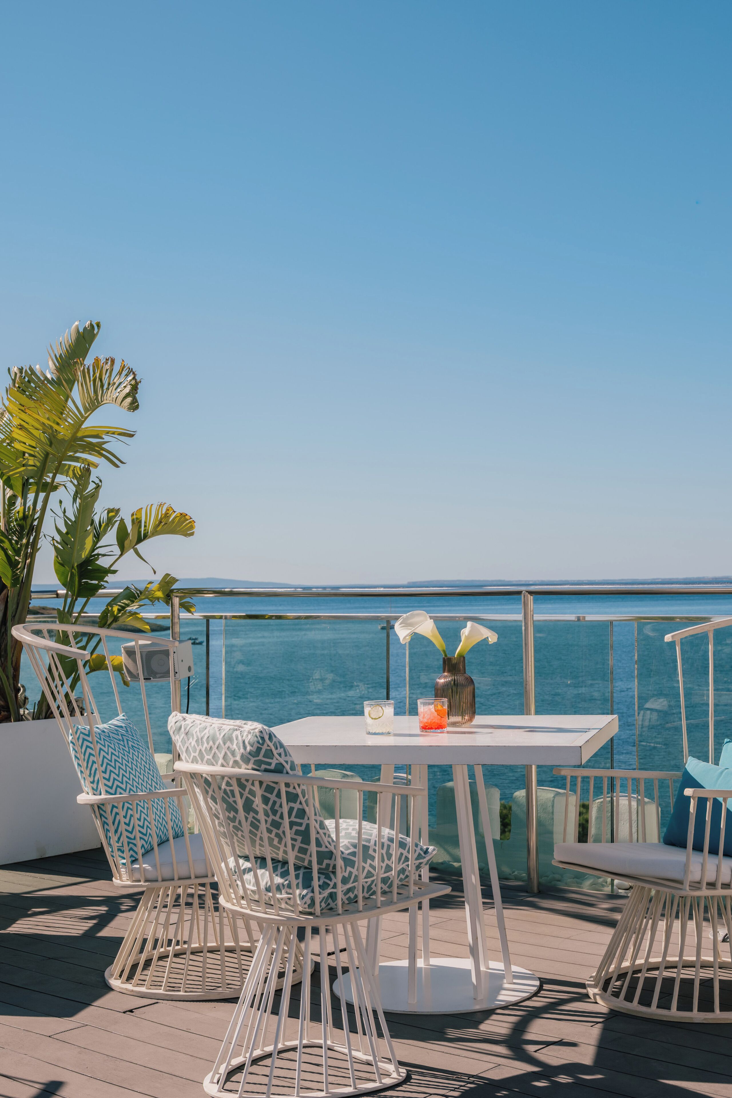 Terraza con mesa y sillas, con vista a un cuerpo de agua.