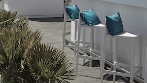 A bar named "SKY BAR" with a modern design, including white bar stools with teal cushions and a sign that reads "Let's party".