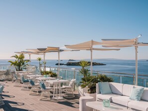Terraza en la azotea con mobiliario exterior, un sofá blanco y vistas al mar.