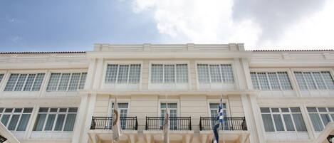 Theoxenia Palace, con fachada clásica, varios balcones y banderas.