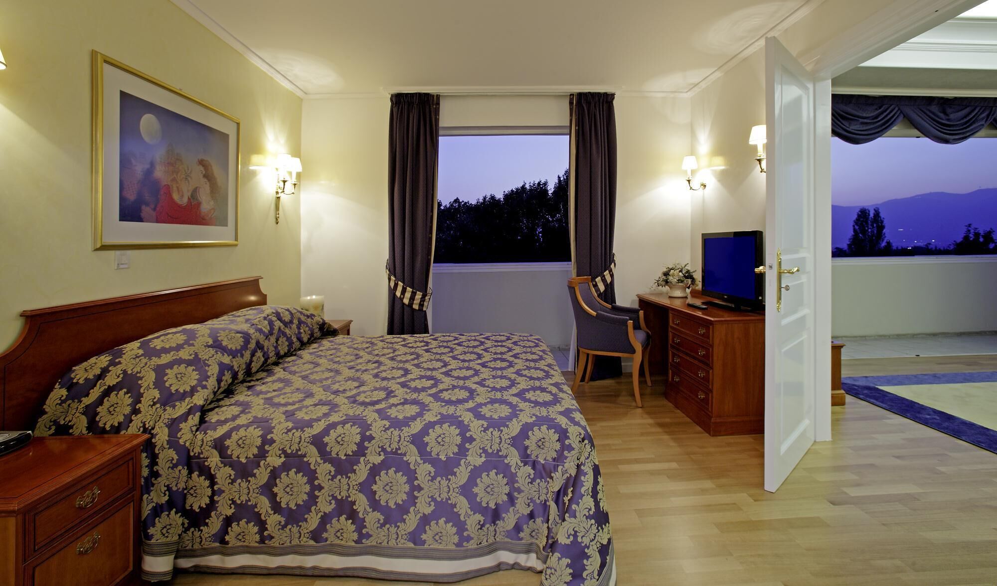 Un dormitorio con cama, escritorio, silla, televisor y ventana con cortinas.