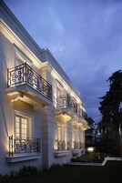 Un edificio de varios pisos con balcones ornamentados y un jardín bien cuidado.
