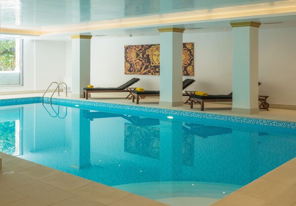 An indoor swimming pool with lounge chairs and a ladder.