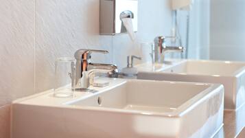 Ein modernes Badezimmer mit zwei Waschbecken, einem Spiegel und einem Handtuchspender.