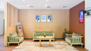 A modern interior with a wooden wall, a green sofa, a round table, and a magazine rack. - ibis Rotorua (Rotorua)