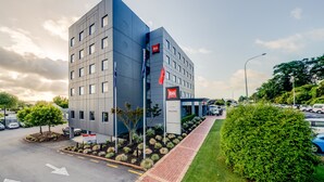 A modern hotel with a flat facade, multiple windows, and a red flag indicating the brand.