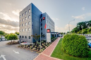 A modern hotel with a flat facade, multiple windows, and a red flag indicating the brand.