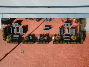 Vista aérea de un patio de hotel con áreas de estar al aire libre, macetas y piso de ladrillo.