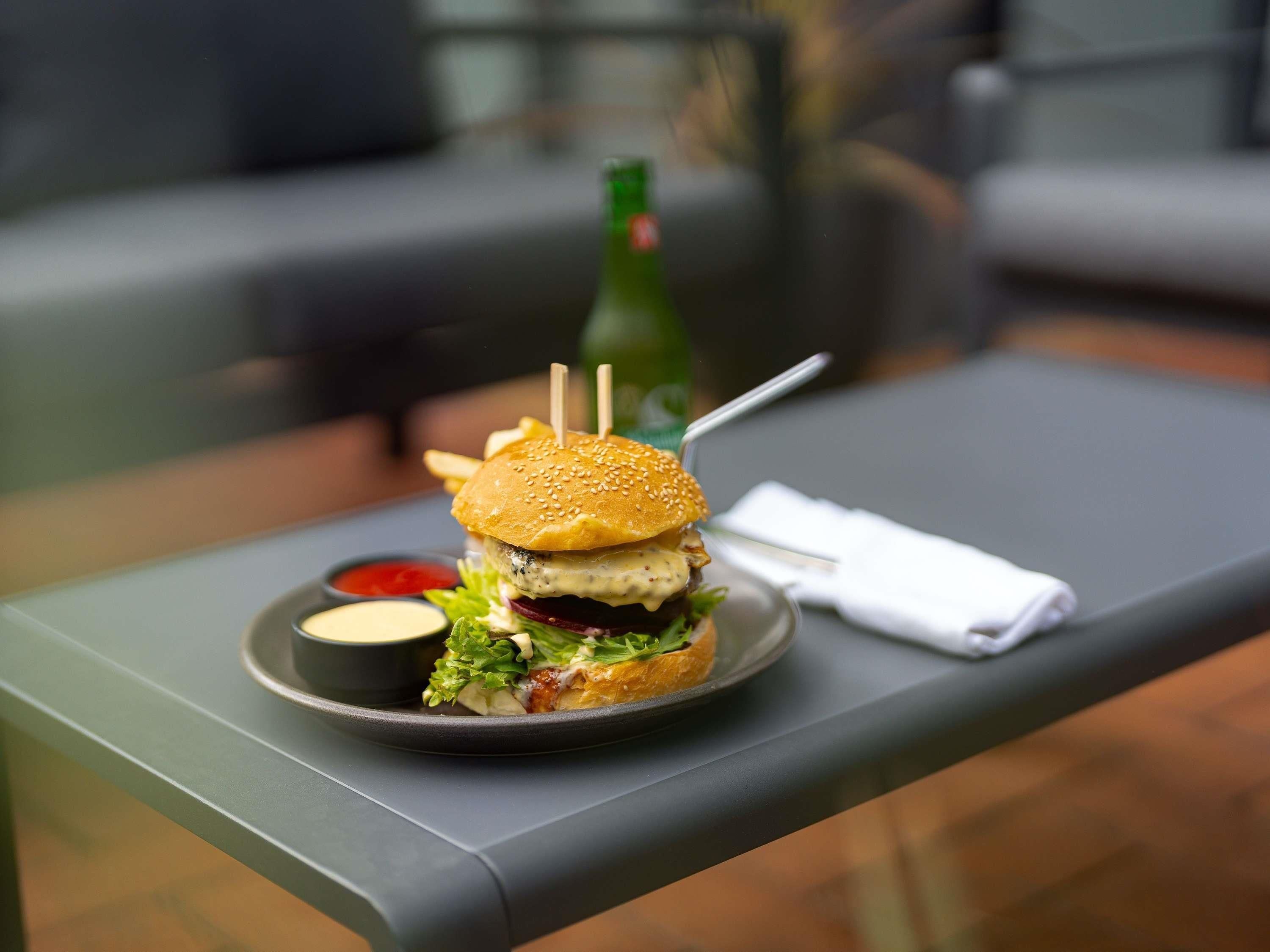 Una comida con una hamburguesa, papas fritas y una bebida sobre una mesa.
