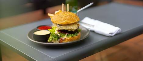 Una comida con una hamburguesa, papas fritas y una bebida sobre una mesa.
