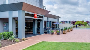 Un bâtiment moderne qui abrite un restaurant appelé « ibis Restaurant » et dispose d’une terrasse.