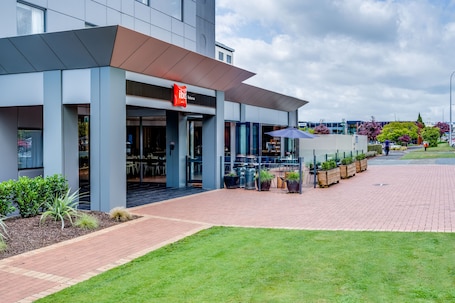 A modern building with a restaurant named "ibis Restaurant" and outdoor seating.