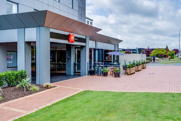 Un bâtiment moderne qui abrite un restaurant appelé « ibis Restaurant » et dispose d’une terrasse.