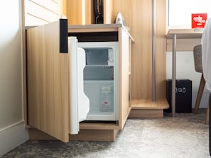 Eine kleine Küche mit integriertem Kühlschrank, einer Mikrowelle und einer Kaffeemaschine.